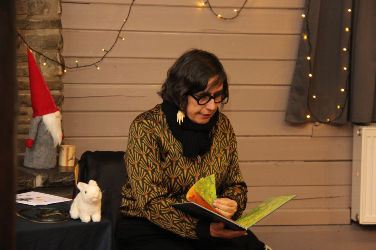 Andrea Karimé sitzt auf einem Stuhl und liest aus dem Buch "Das kleine Kamel Soraya"