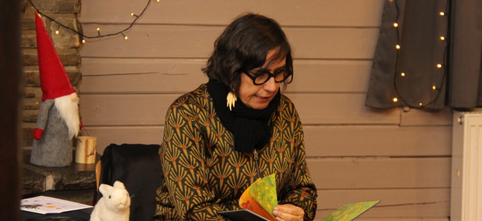 Andrea Karimé sitzt auf einem Stuhl und liest aus dem Buch "Soraya, das kleine Kamel"